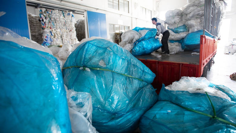 عامل صيني يفرغ حمولة شاحنة من النفايات البلاستيكيّة في مصنع لإعادة التدوير في لو سيان/Saša Petricic/CBC/هيئة الاذاعة الكنديّة