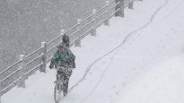 A cyclist rides a bicycle along the Rideau Canal during a spring snow storm in Ottawa