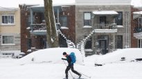 A man cross-country skis past cars buried in snow as a late winter storm that dumped more than two feet (60 cm) of snow in Montreal