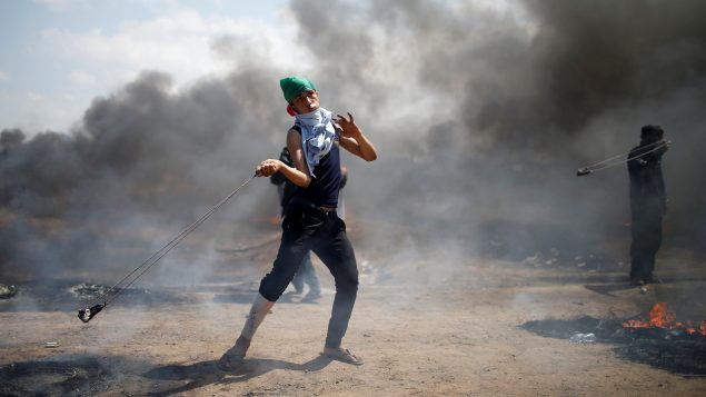 متظاهر فلسطيني في غزّة يرشق القوّات الاسرائيليّة بالحجارة في 14-05-2018/Mohammed Salem/REUTERS