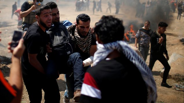 إجلاء جريح فلسطيني أصيب برصاص القوّات الاسرائليّة خلال المظاهرات التي جرت في غزّة في 14-05-2018/(Mohammed Salem/REUTERS