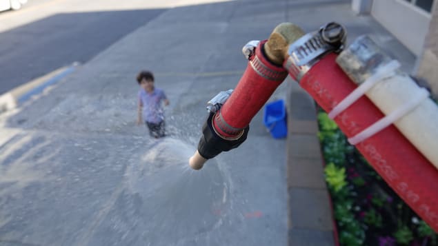 طفل ينظر إلى آليّة تابعة لأجهزة الاطفاء ترشّ المياه في أحد شوارع مونتريال/ Radio-Canada/Simon-Marc Charron