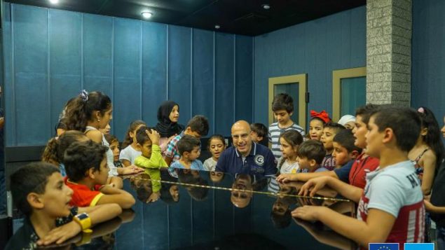 الموسيقي اللبناني جاد رحباني مع مجموعة من الأطفال يشاركون في ورشة عمل موسيقيّة في إطار مشروع "البوم 11" الذي اطلقته منظّمة اليونيسيف/موقع اليونيسيف