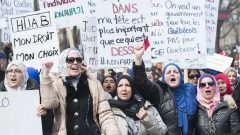 ينص مشروع القانون 21 حول عَلمَنة الدولة في كيبيك على حظر ارتداء الرموز الدينية على موظفي الدولة في وضع قسري (القضاة ، ضباط الشرطة ، المدعون العامون ، حراس السجون) ، وخاصة معلمي المدارس الابتدائية والثانوية المنتمين إلى القطاع العام - Radio Canada
