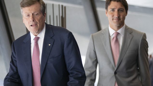 رئيس الحكومة جوستان ترودو (إلى اليمين) يدخل القصر البلدي في تورونتو إلى جانب العمدة جون توري/Chris Young/CP