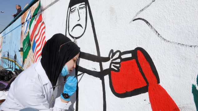 سيّدة عراقيّة ترسم جداريّة في أحد شوارع بغداد في 21-11-2019/Khalid Al-Mousily/Reuters