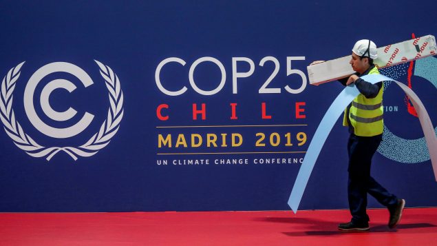 عامل يسير أمام شعار مؤتمر المناخ في مركز المؤتمرات في مدريد في 30-11-2019/Sergio Perez/Reuters