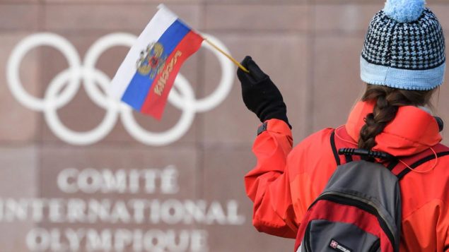 سيّدة تلوّح بعلم روسيا أمام مقرّ اللجنة الدوليّة الأولمبيّة في لوزان في سويسرا/ Fabrice Coffrini/Getty Images