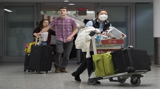 مسافرة تضع قناعا للوقاية من فيروس كورونا عند وصولها إلى مطار بيرسون في تورونتو يوم 25.01.2020 - The Canadian Press / Nathan Denette