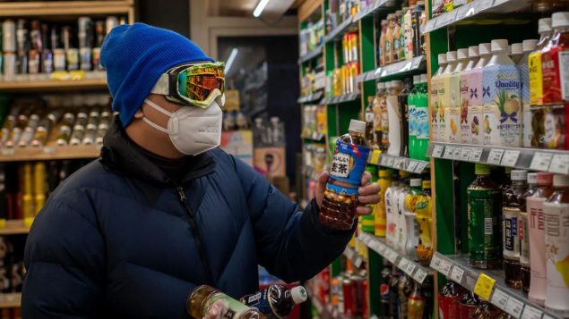 متسوّق في متجر في بكين يضع نظّارات وقناعا طبيا واقيا /AFP VIA GETTY IMAGES / NICOLAS ASFOURI