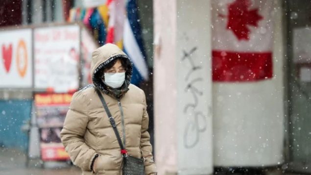 سيّدة تضع كمّامة في أحد شوارع تورونتو للوقاية من فيروس كورونا/Nathan Denette/CP