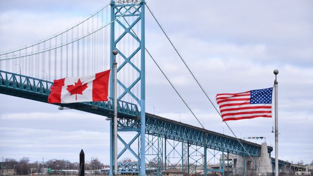العلمان الكندي والأميركي يرفرفان فوق معبر أمباسادور الحدودي في وندسور في مقاطعة أونتاريو على الحدود الكنديّة الأميركيّة/Rob Gurdebeke/CP