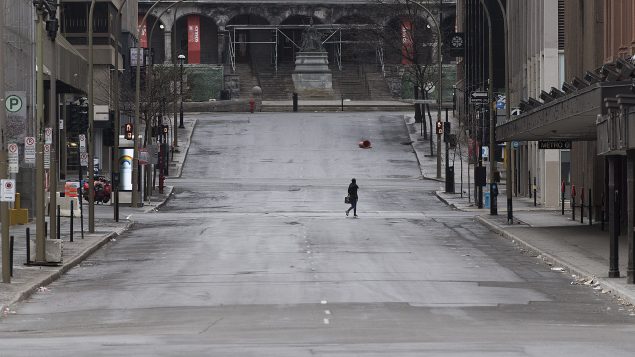 A woman crosses a street in downtown Montreal, Sunday, April 5, 2020, as Coronavirus COVID-19 cases rise in Canada and around the world.THE CANADIAN PRESS/Graham Hughes