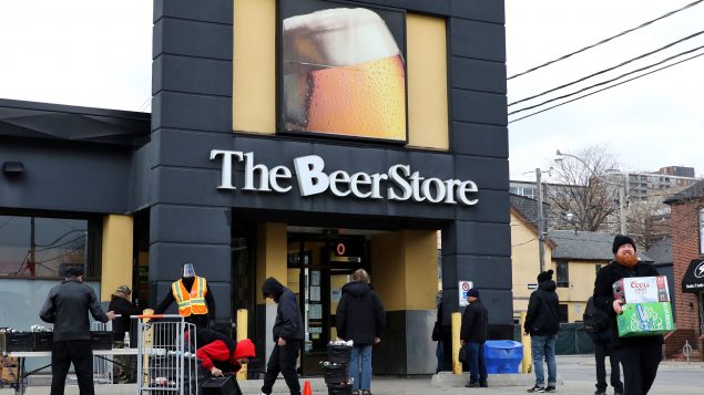 أشخاص ينتظرون أمام متجر للجعة (البيرة) في تورنتو لشراء الجعة وإعادة زجاجات فارغة مع التزامهم بقاعدة التباعد الجسدي في 20-04-2020/Colin Perkel/CP