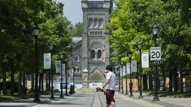 شخص وضع كمّامة يسير امام جامعة تورونتو/Nathan Denette/CP