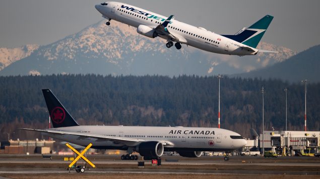 طائرة تابعة لشركة ويست جيت في الأجواء وأخرى تابعة للخطوط الجويّة الكنديّة على المدرج في مطار فانكوفر في 20-03-2020/Darryl Dyck/CP