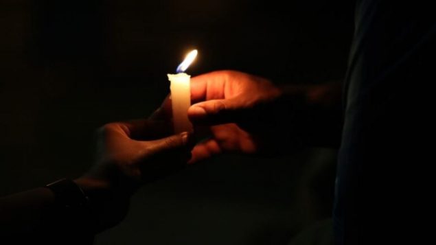 في ذكرى مرور عام على الجائحة، أضاء المشاركون في الحفل الافتراضي في ساسكاتون شمعة أمام نافذتهم تنير درب المسافرين المُتعبين وسط الظلام/Derek Spalding/CBC