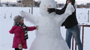 A Syrian man and his daughter make a snowman at the refugee camp in al-Majdal village, Bekaa Valley, East Lebanon on Jan. 8, 2015. A powerful winter storm swept through the region, killing several Syrian refugees in Lebanon and forcing thousands of others who have fled their country's civil war to huddle together for warmth. Photo Credit: AP / Hussein Malla