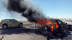 The 2014 race goes on, right past the burning wreckage of Kazakhstani drivers Bauyrzhan Issabayev and Gabdulla Ashimov's car, during the second stage of the Dakar Rally from San Luis to San Rafael, Argentina, on Jan. 6. (Jean-Paul Pelissier/Reuters)