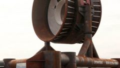The OpenHydro turbine showing scale with the two engineers at lower left. The vanes of this stationary turbine rotate clockwise or counterclockwise depending on direction of the tide. (CLICK to ENLARGE)