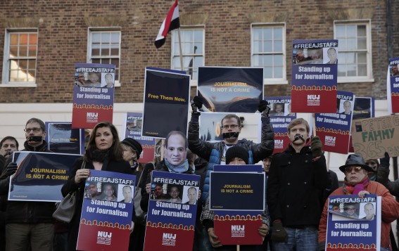 Demonstrators, some with black tape over their mouths to illustrate the silencing of free speech and journalists, hold up placards as they demonstrate across the street from the Egyptian Embassy to mark a year since the detention of Al-Jazeera English journalists in Egypt, central London, Monday, Dec. 29, 2014. The unprecedented arrest and prosecution of Australian Peter Greste, Egyptian-Canadian Mohammed Fahmy and Egyptian Baher Mohammed sent a chill through the media in Egypt. They were detained in a raid on suspicion of helping the Muslim Brotherhood, which the government later declared a terrorist organization, and were sentenced to between seven and 10 years in prison in a trial that most observers called a politicized sham that lacked any evidence to incriminate the journalists of anything beyond doing their job. (AP Photo/Lefteris Pitarakis)