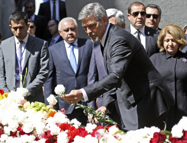 US actor George Clooney, foreground, puts a flower, as he attends a ceremony at a memorial to Armenians killed by the Ottoman Turks, in Yerevan, Armenia on Sunday, April 24, 2016. Vahan Stepanyan/ PAN Photo via AP