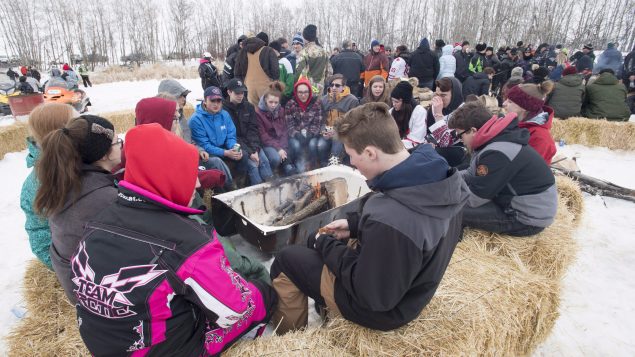 People sitting on haystacks in the snow.