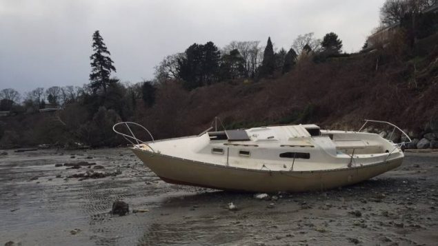 abandoned small sailboat washed up on shore.