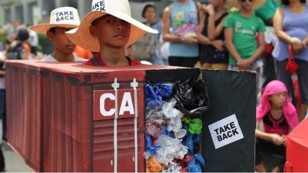 Filipino environmental activists wear a surprisingly realistic representation of a shipping container of garbage iner van filled with garbage to protest the cargo containers of garbage that were shipped from Canada to the Philippines in 2013 and 2014 (Aaron Favila/Associated Press)