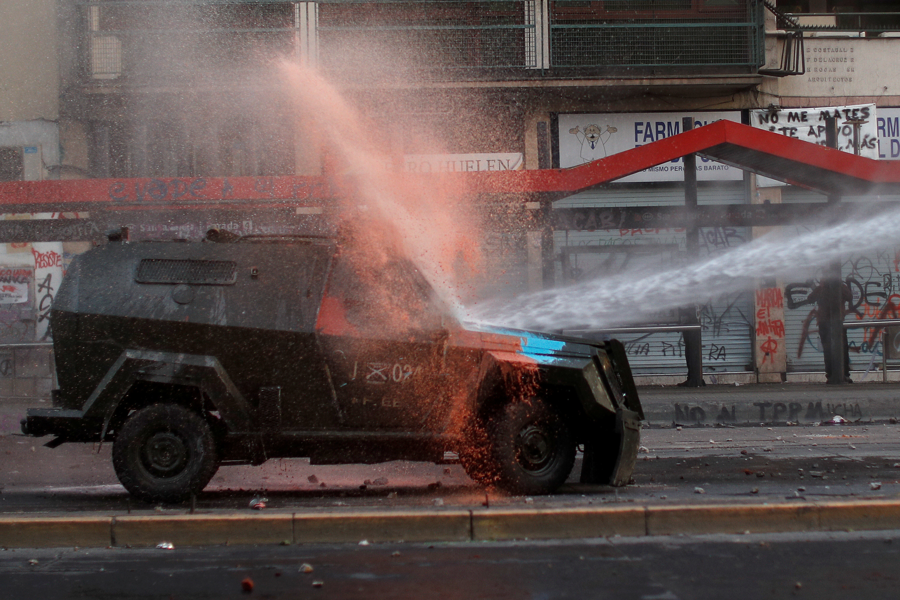 A riot police vehicle is sprayed by a water cannon during a protest against Chile’s government in Santiago, Chile October 29, 2019. (Jorge Silva/Reuters)