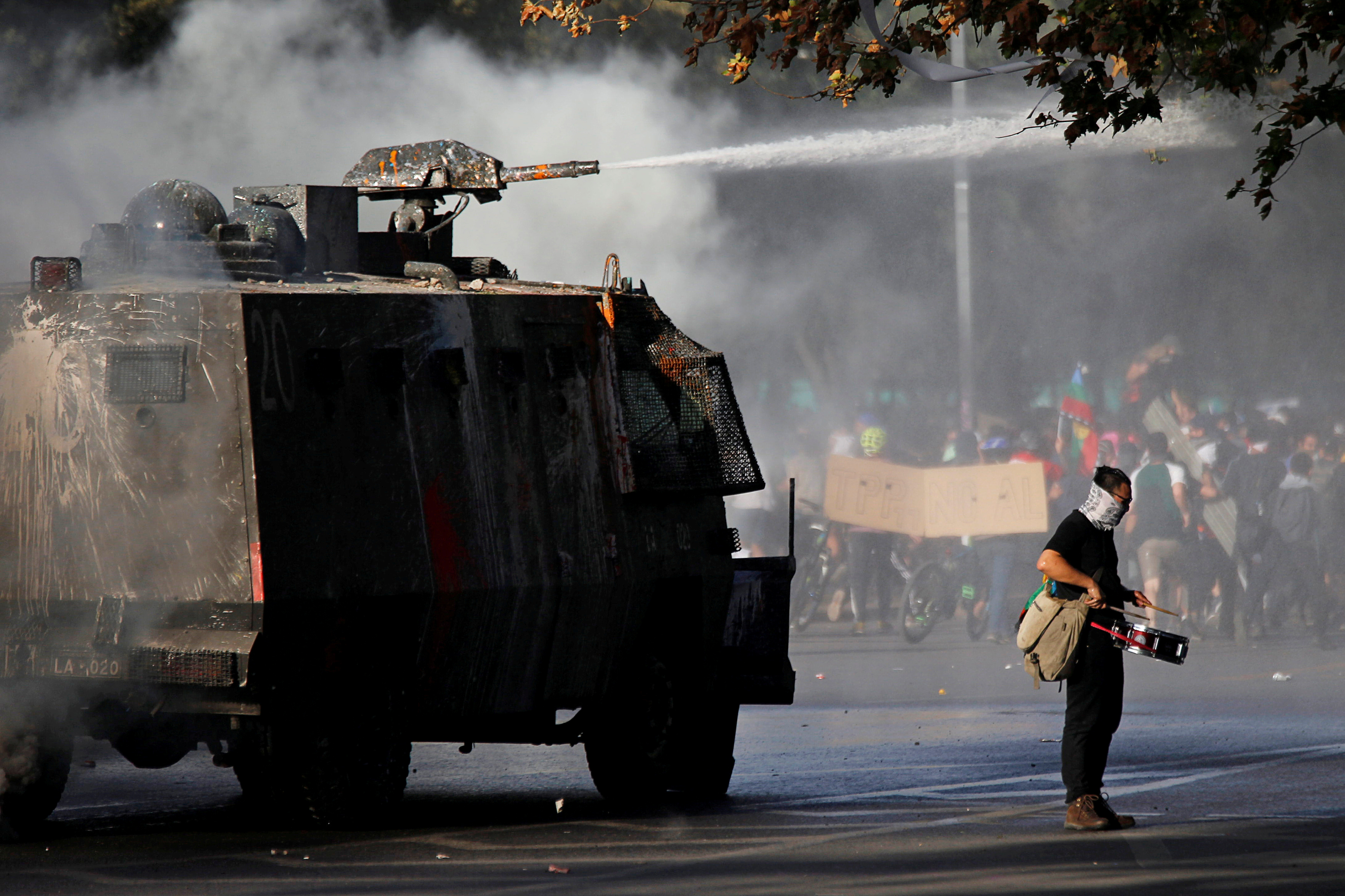 A demonstrator plays the drum as a police vehicle uses a water cannon during an anti-government protest in Santiago, Chile October 30, 2019. (Edgard Garrido/Reuters)