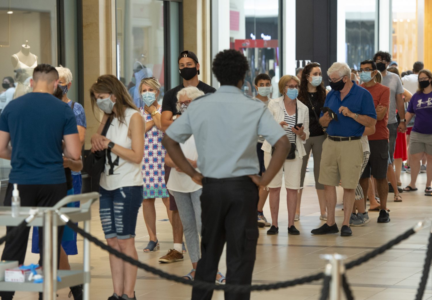Shoppers wear masks as they line up at a mall RCI English
