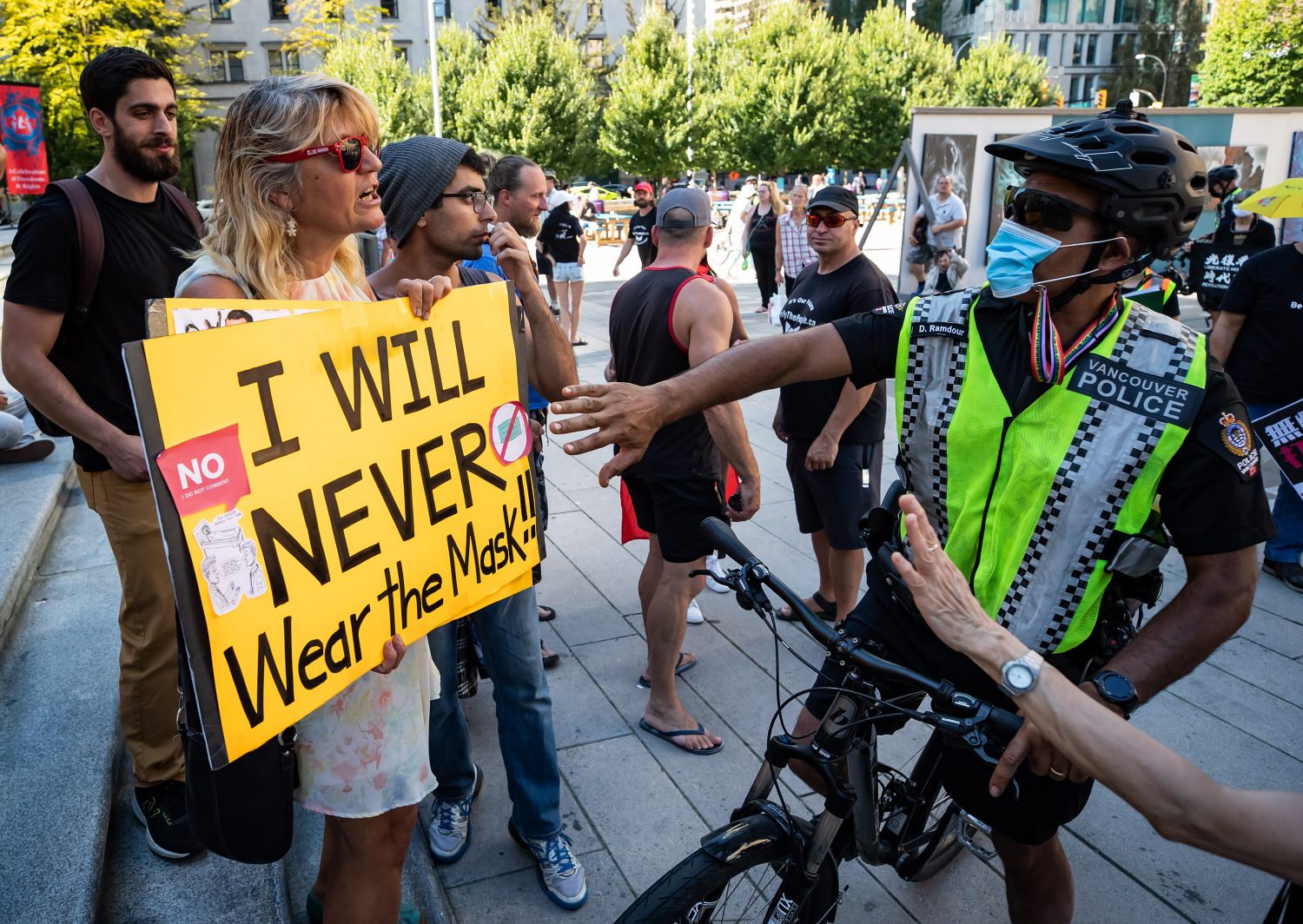 A police officer steps in to move anti-mask protesters away, in