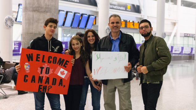 People at airport holding signs welcoming newcomers.