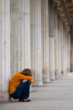 Sad girl is sitting near columns