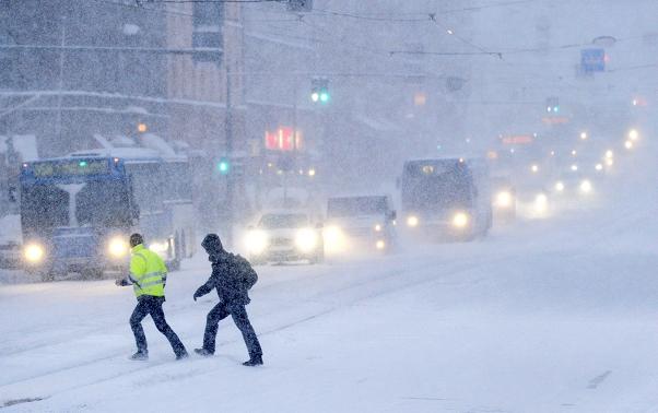 People cross a snow covered road on February 3, 2012 in Helsinki. Photo: Vesa Moilanen, Lehtikuva, AFP Photo.   