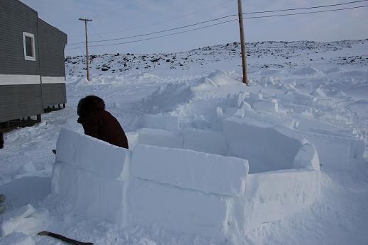 Ulukhaktok elder continues work on his annual igloo. The school principal had students come out to help the elder lift the heavy snow blocks. Photo: Eilís Quinn, Radio Canada International. 