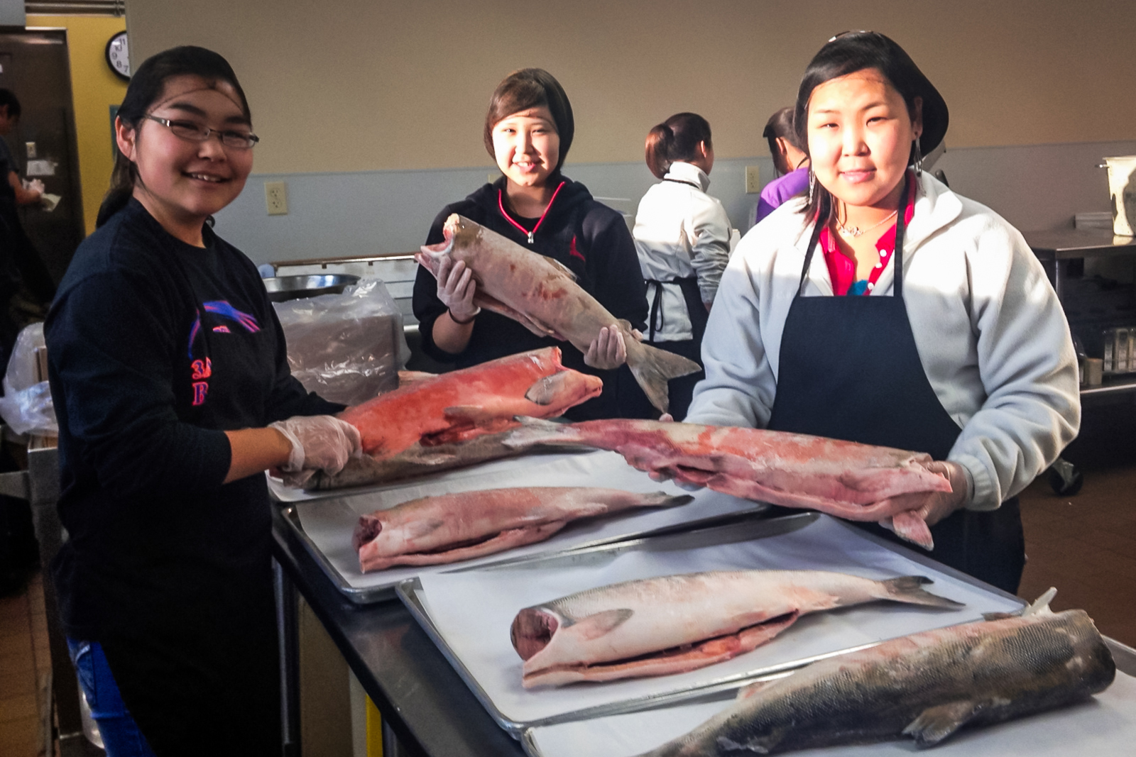 From left, Rudi Joseph from Hooper Bay, Freida Sage from Kivalina, and Charlene Ayagalria from Napakiak prep salmon for a school meal. November 7, 2012. Photo courtesy Galena School. Alaska Dispatch.