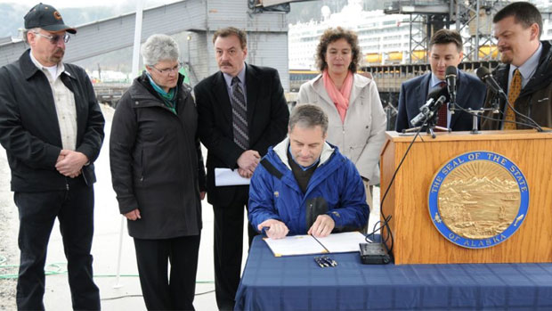 Whitehorse Mayor Bev Buckway, second from left, and other officials watch as Alaska Gov. Sean Parnell, seated, signs House Bill 119 into law Friday at the Skagway Ore Terminal in Skagway, Alaska. (Office of the Governor of Alaska)