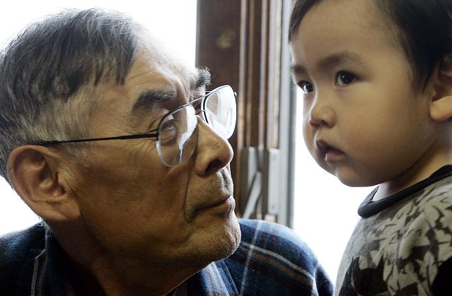 Johnny Weyiouamma Sr. looks at his grandson Keith in Shishmaref, Alaska. What will northern development mean for Arctic residents like them? AFP PHOTO/GABRIEL BOUYS 