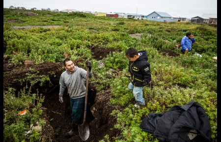 Gambell residents Travis Kaningok, his 3-year-old son Travis Jr., and fiancee Roxanne Campbell digging for old bones, ivory and artifacts on St. Lawrence island. August 29, 2012. Photo: Loren Holmes. Alaska Dispatch. 