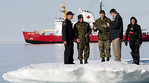 Prime Minister Stephen Harper, second from right, talks with Chief of the Defence Staff General Walter Natynczyk (centre) as they take part in a training exercise in Resolute, Nunavut on Aug. 25, 2010. The Canadian Coast Guard's medium icebreaker Henry Larsen is seen in Allen Bay. Canadian activity in the North, from searching for the Franklin expedition wreck to military manoeuvres, are about establishing sovereignty, experts say. (Sean Kilpatrick/Canadian Press)