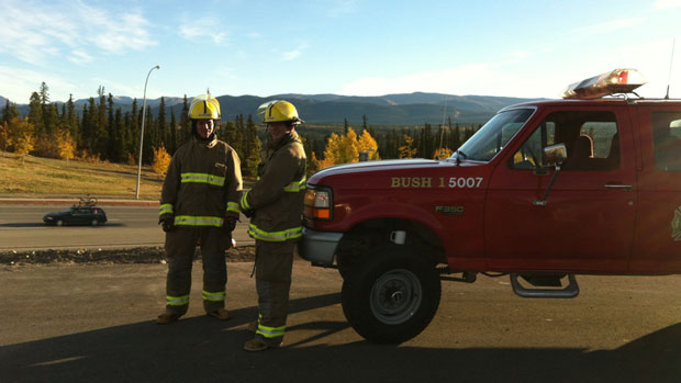 Whitehorse firefighters stand outside their station on Two Mile Hill Thursday morning to let people know to report emergencies directly to them while 911 service was down. (David Croft/CBC)