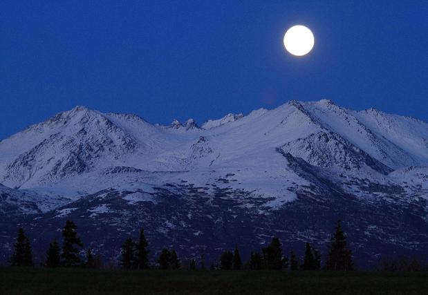 The moon rises over the Chugach Mountains on Sunday, Sept. 30, 2012, in Anchorage, Alaska. (AP Photo/Dan Joling)