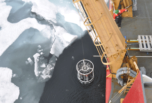 A crane lowers sample bottles into the Arctic Ocean to collect water from underneath the sea ice. (Gert van Dijken)