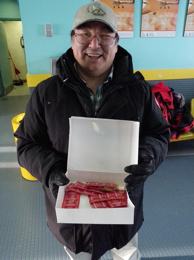 Daniellie Qinuajuak, community liaison wellness worker, distributing condoms in Akulivik airport. Photo by Eilís Quinn.