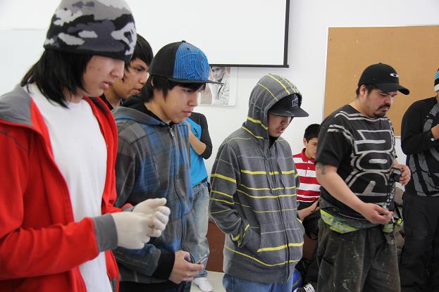 Youth from Deline watching wildlife officer preparing a marten skin after trapping. Photo: Eilís Quinn, Radio Canada  International. 