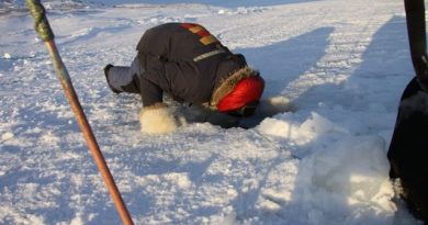An Inuit hunter peers into a hole in the ice to check his fishing nets. Photo by Levon Sevunts.