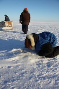 A young Inuit hunter looks into a seal breathing hole in the sea ice near Clyde River, Nunavut. (Levon Sevunts)