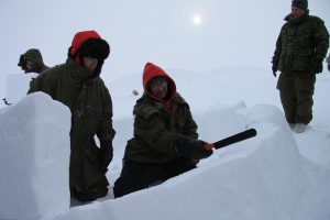 An Inuit Ranger shows how to slant the walls of the igloo and how to fit the snow blocks together using nothing more than a snow machete or a long kitchen knife. Photo by Levon Sevunts.